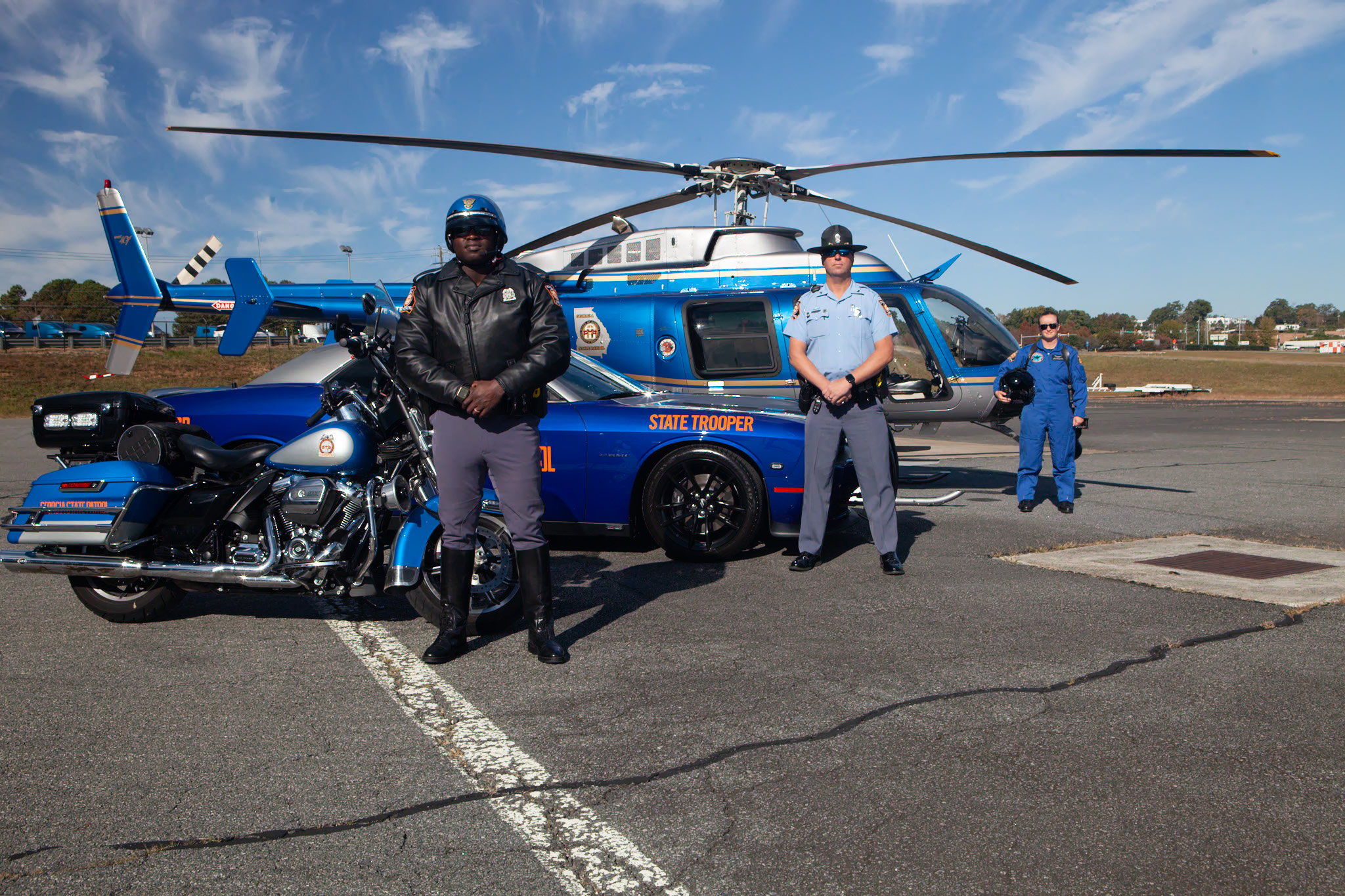 Georgia State Patrol motor trooper, aviation pilot, and motorcycle officer with patrol vehicle and helicopter